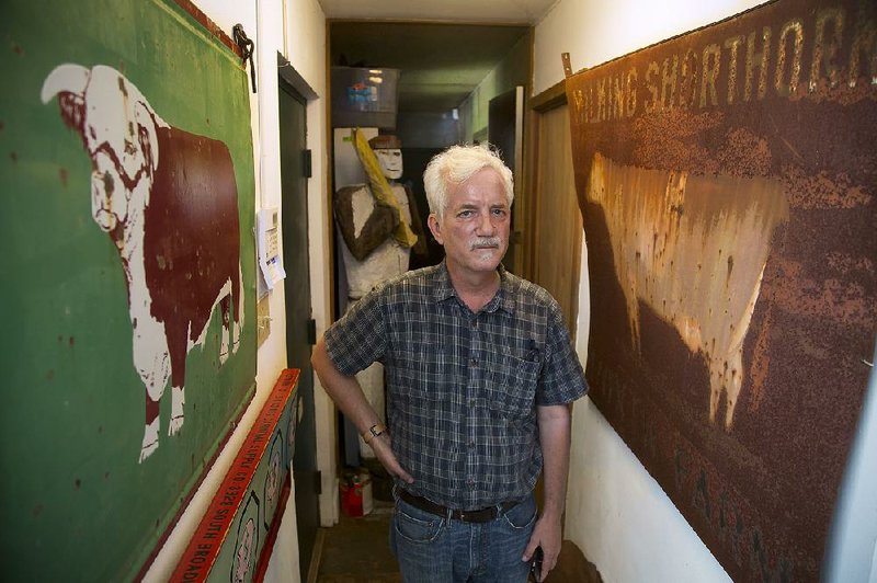 Tim Hursley, an internationally renowned architecture photographer, stands between two rural signs that are part of his collection of Americana objects. The Little Rock resident won the top award at this year’s “Delta Exhibition” at the Arkansas Arts Center.