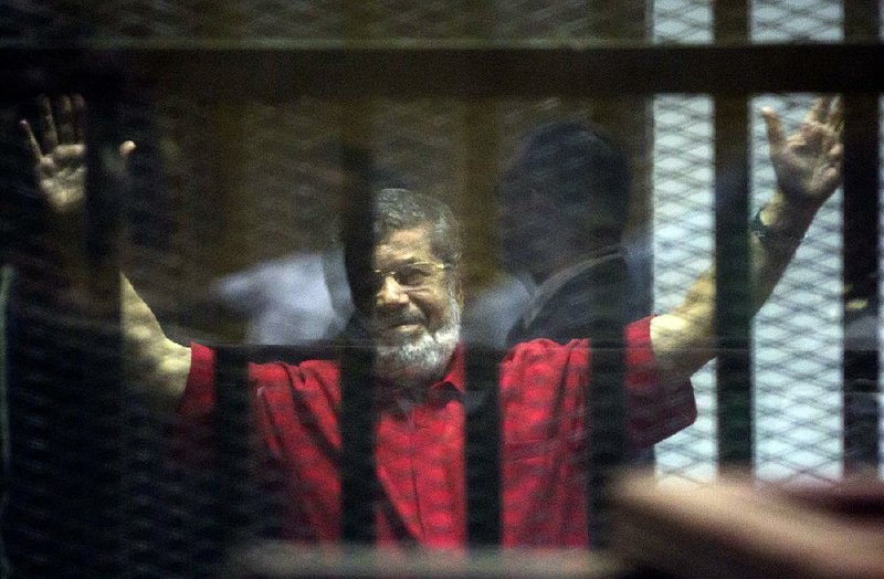 Former Egyptian President Mohammed Morsi stands inside a defendant cage Saturday at a makeshift courtroom at a police academy in Cairo.