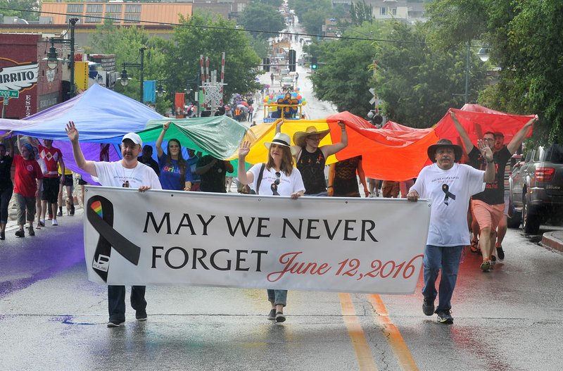 Gary McClaskey (from left), Anna Rainey and Derry Jacob lead the Northwest Arkansas Pride Parade up Dickson Street on Saturday in Fayetteville.