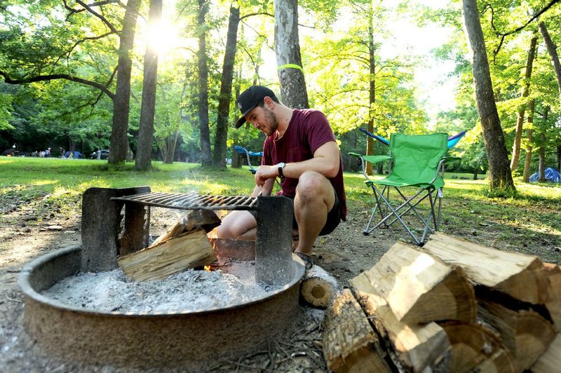 Loren Cavener of Tulsa lights a fire while camping June 10 at Devil’s Den State Park near Winslow.