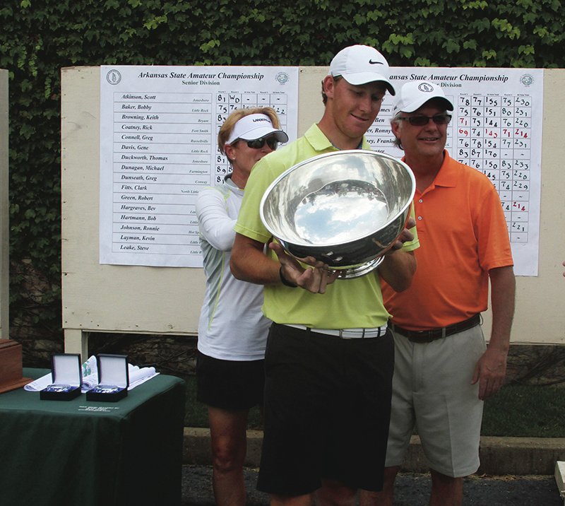 The Sentinel-Record/Elisha Morrison GOLLY GEE: Carrie, left, and Tim Hall, right, both of Bismarck, present Benton's Austin Eoff with the E.B. Gee Trophy for winning his second consecutive Arkansas State Golf Association State Amateur Sunday at Hot Springs Country Club. Eoff won by one stroke at 12 under par.