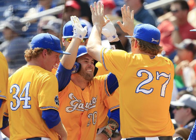 UC-Santa Barbara’s Dempsey Grover (center) is met by teammates after scoring a run in the sixth inning of Monday’s College World Series game against Miami. The Gauchos held on to beat the Hurricanes 5-3, eliminating them from the tournament.