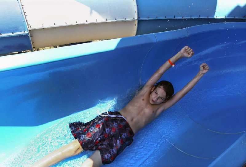 Luke Owen, 12, of Lamar zooms down a water slide Monday afternoon at Splash Zone water park in Jacksonville. The first day of summer continued a stretch of 90-degree days in the state and region.