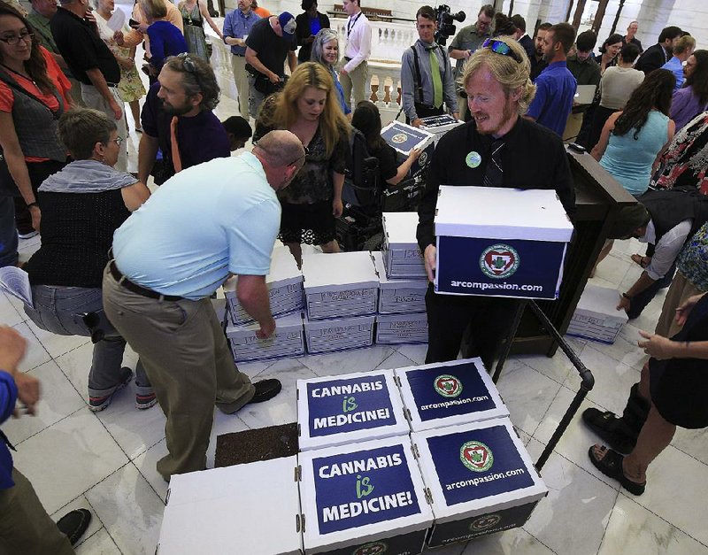 Supporters of a proposed ballot initiative on the medical use of marijuana load signed petitions onto a cart Monday at the state Capitol after an Arkansans for Compassionate Care news conference.