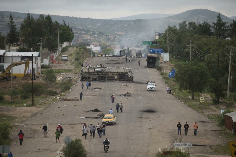 People walk on the still blocked highway in Oaxaca state, Mexico, Monday.
