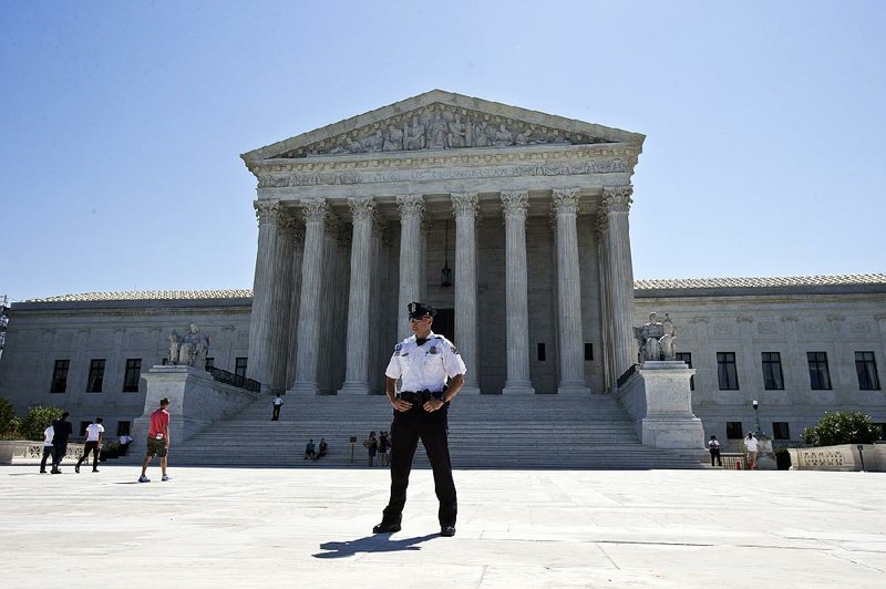 A Supreme Court police officer stands guard in front of the Supreme Court building in Washington on Monday as the court announced several decisions.