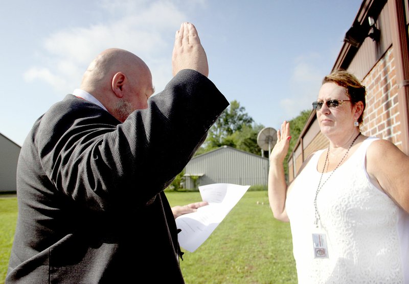 LYNN KUTTER Wanda Bierber, right, takes the oath of office from Tim Doc Marion, manager of Post Office Operations for Northwest Arkansas. Bieber is the new postmaster at Prairie Grove Post Office.