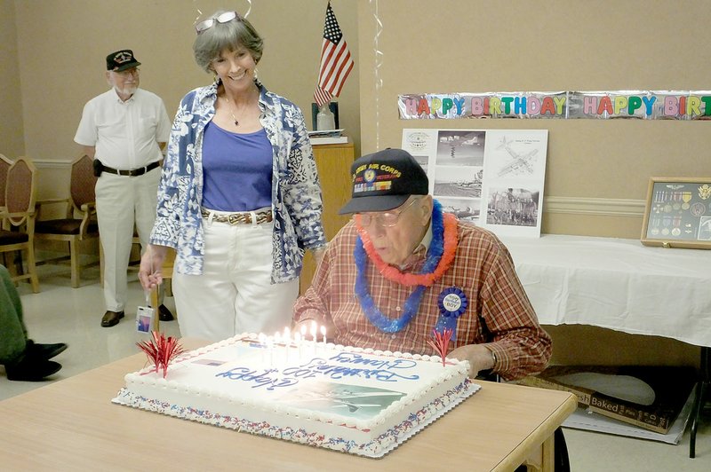 Lynn Atkins/The Weekly Vista Shirley Kellogg watches her father, Harvey Brown, blow out the candles on the cake that commemorates his 100th birthday at Highlands Health Care on Thursday. Brown, a veteran of the U.S. Army Air Corps, flew 30 missions over Europe as a bombardier during World War II. His son in law, Jack Kellogg, presented him with a cap decorated with his medals from the service. The local chapter of the American Legion presented him with a certificate. Brown has lived in Bella Vista since 1989.