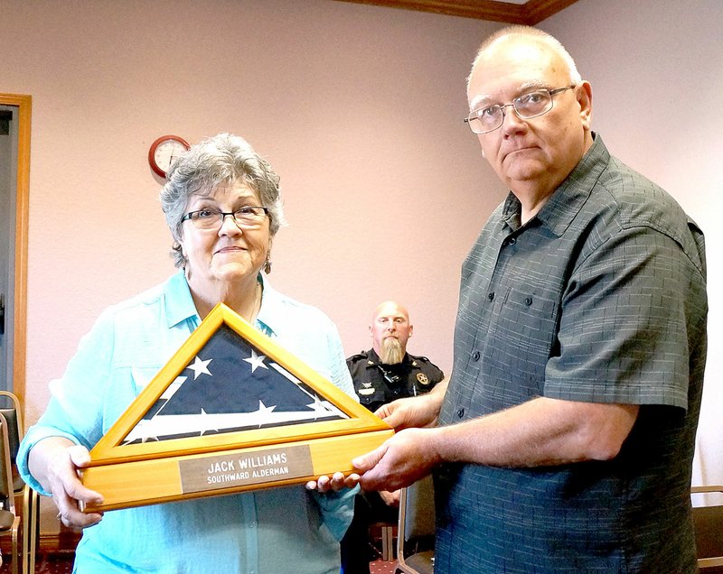 Rita Greene/McDonald County Press Mayor Gregg Sweeten presented Barbara Williams, wife of deceased Jack Williams who was a former Alderman on the Pineville city council, with a framed flag plaque honoring the service and memory of Jack Williams at the Pineville city council meeting Tuesday.