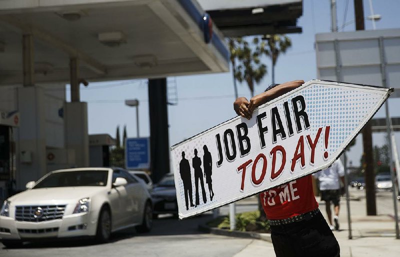 A sign company employee promotes a job fair Wednesday in Los Angeles. Nationally, weekly applications for unemployment benefits have fallen in the past few weeks.