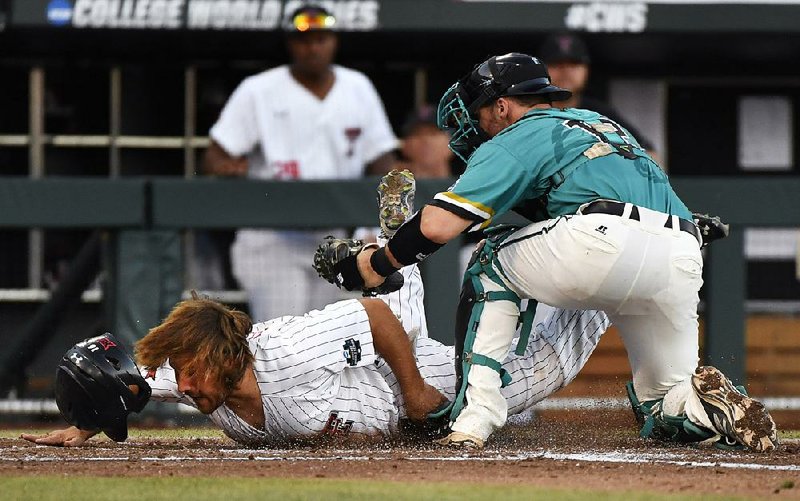 Texas Tech baserunner Tyler Floyd (left) dives to score ahead of the tag by Coastal Carolina catcher David Parrett in the second inning of Thursday’s NCAA College World Series game in Omaha, Neb. Coastal Carolina held on to win 7-5 and eliminate Texas Tech.
