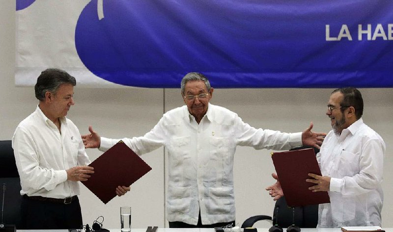 Cuba’s President Raul Castro (center) oversees the signing of the Colombia cease-fire Thursday in Havana, bringing together Colombian President Juan Manuel Santos (left) and Rodrigo Londono of the Revolutionary Armed Forces of Colombia.