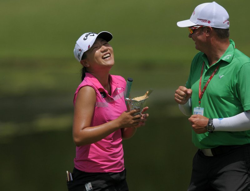 Lydia Ko has a laugh with her caddy after playing through on the 18th green Thursday during the Wal-Mart NW Arkansas Championship at Pinnacle Country Club in Rogers.