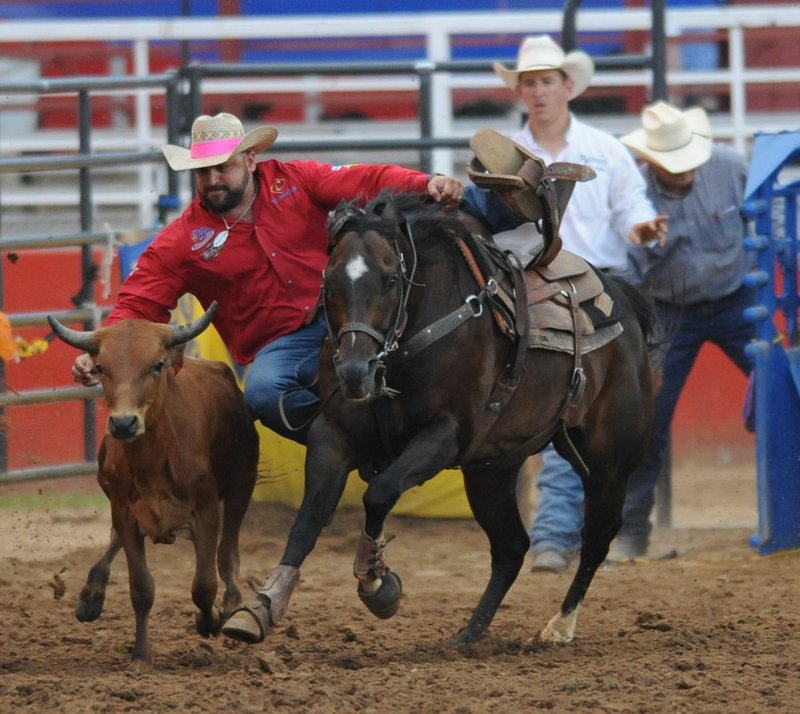 Jon Carpenter of Whiteboro, Texas, originally from Atkins, competes Thursday in the steer wrestling. during the 72nd Rodeo of the Ozarks at Parsons Arena in Springdale. Visit nwadg.com/photos to C see more photographs from the rodeo.