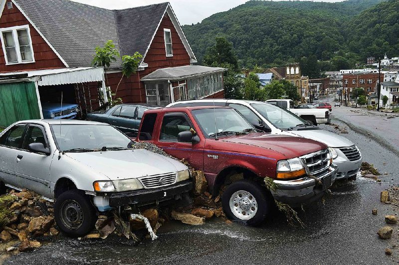 Cars and rocks sit smashed together after floodwaters pushed them along a street Friday in Richwood, W.Va. 
