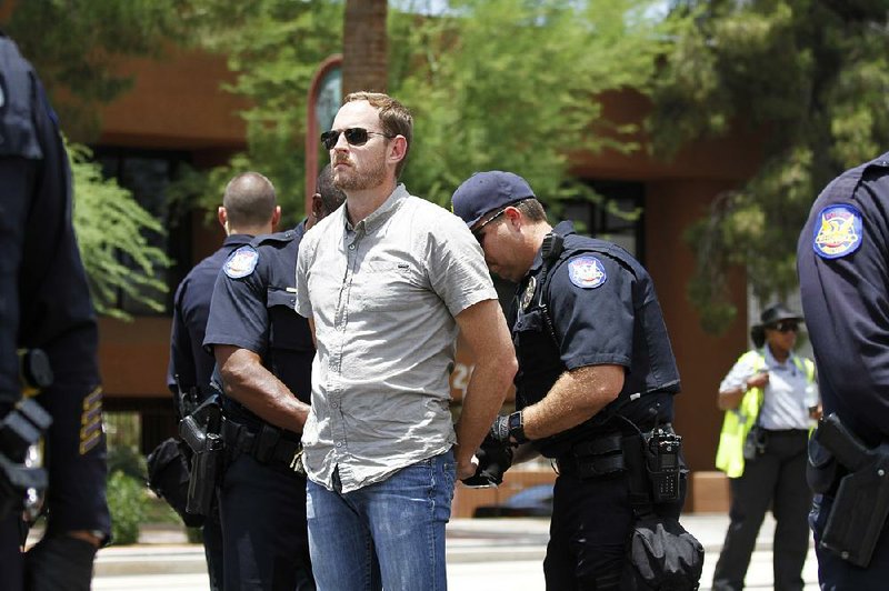 Police officers restrain a man Thursday in Phoenix from a protest mounted by than 60 people after the U.S. Supreme Court’s deadlock on President Barack Obama’s immigration order. 