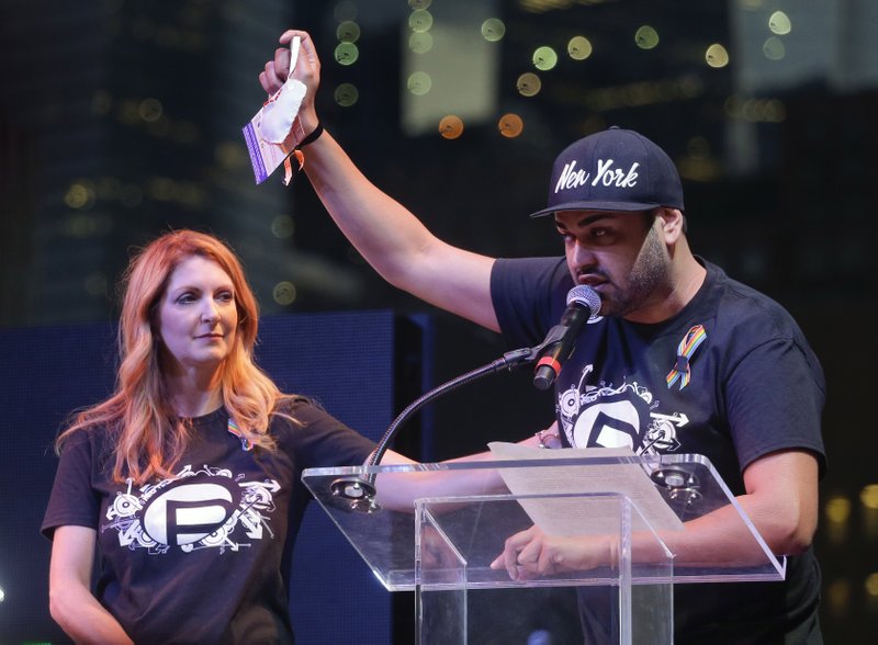 Pulse night club entertainment manager Neema Bahrami (right) holds up a card made for him by children in honor of the Orlando shooting victims as club owner Barbara Poma listens Friday during a gay pride rally in New York. 