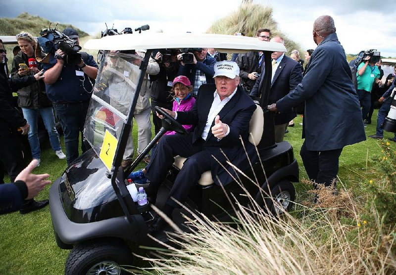 Donald Trump stops to talk with reporters Saturday as he rides the Trump International Golf Links at Balmedie, Scotland, near Aberdeen, with his granddaughter Kai. 