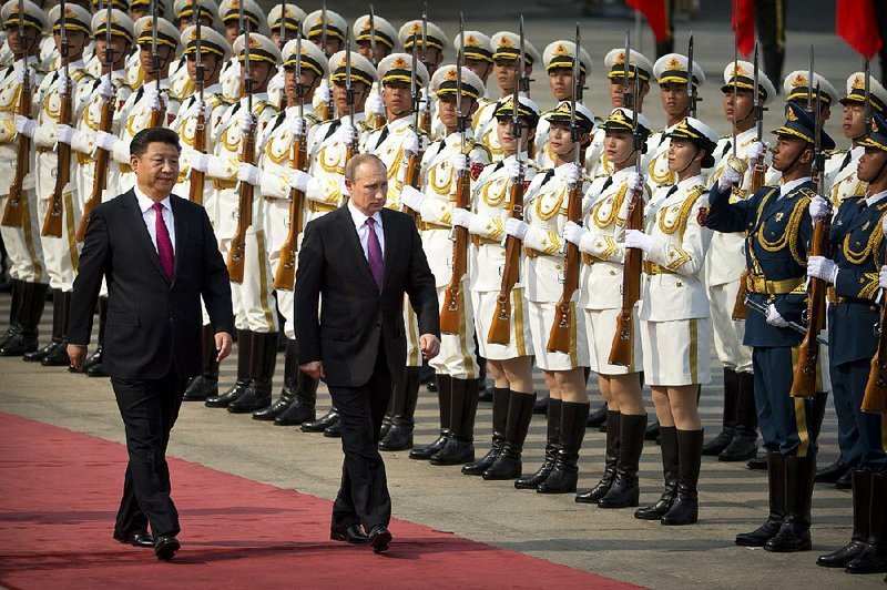 Russian President Vladimir Putin (right), escorted by Chinese President Xi Jinping, reviews an honor guard during a welcoming ceremony Saturday at the Great Hall of the People in Beijing. 