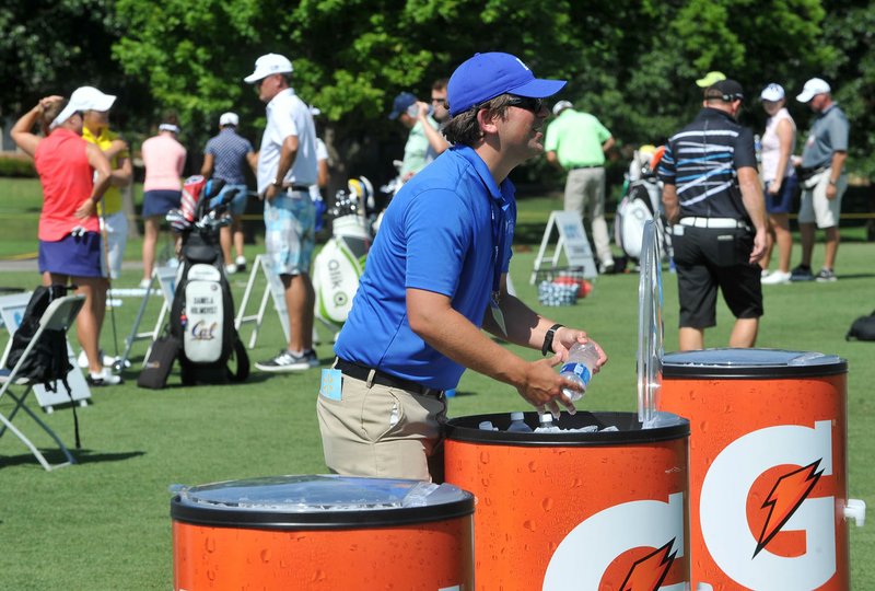 Neal McAllister, a tournament volunteer, helps restock water for golfers on the driving range Wednesday at Pinnacle Country Club in Rogers during the Wal-Mart NW Arkansas Championship. It’s McAllister’s eighth year volunteering at the tournament.