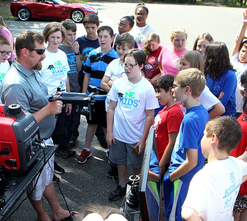 The Sentinel-Record/Richard Rasmussen ArkUAV founder and pilot Brad Fausett, left, explains the components and functions of one of his unmanned aerial vehicles Friday to Kids' College students on the National Park College campus. Fausett offered a flight demonstration and answered questions about his business and the future of drones. William Polk, associate vice president for technical education at the college, led the "Up-Up and Away-Drone Education 101" class throughout the week. More than 70 students attended Kids' College this week with other classes offered in the areas of sign language, cooking, singing, first response and the automotive electrical system.