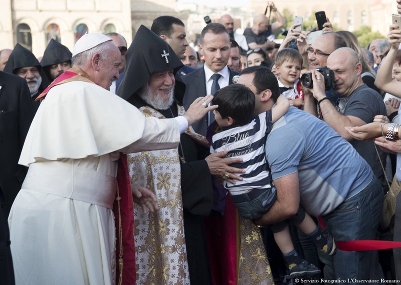 Pope Francis and Catholicos Karekin II, right, reach out to touch a child during an Ecumenical encounter and prayer for Peace in Yerevan’s Republic Square, Armenia, Saturday. Pope Francis is on a three-day trip to Armenia. 