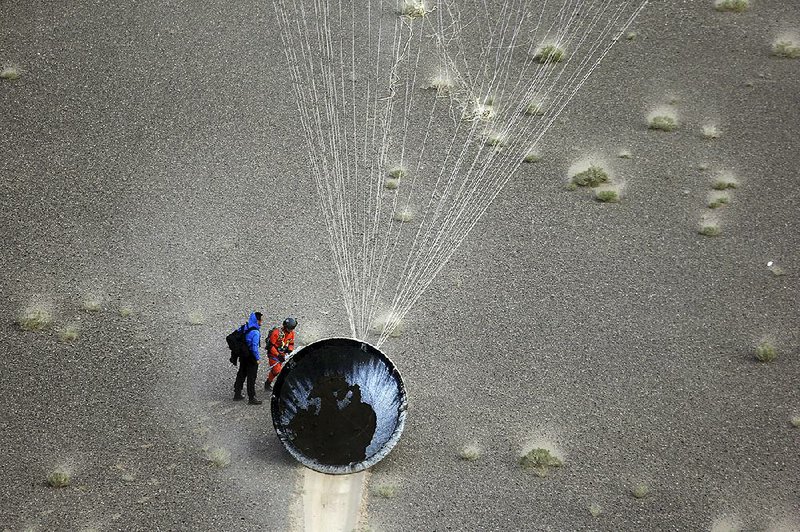 Workers retrieve a re-entry module that was aboard the carrier rocket Long March-7 after it touched down successfully in Badain Jaran Desert in northern China’s Inner Mongolia Autonomous Region on Sunday in this photo released by the Xinhua News Agency.