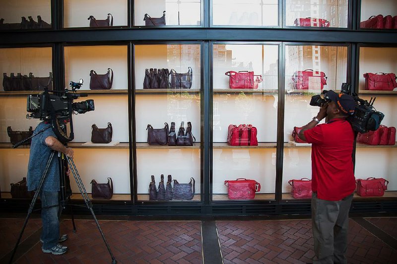 TV cameramen film handbags displayed at Coach Inc.’s new offices at 10 Hudson Yards in New York. Sales of lower-market designer bags such as Coach and Kate Spade are in decline, while demand for higher priced luxury leather products has increased.