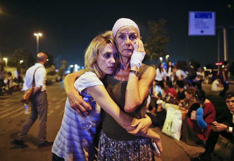 Travelers embrace early today as they wait outside Istanbul’s Ataturk airport after Tuesday’s suicide attack. Officials said it was likely that the Islamic State group was behind the attack. 