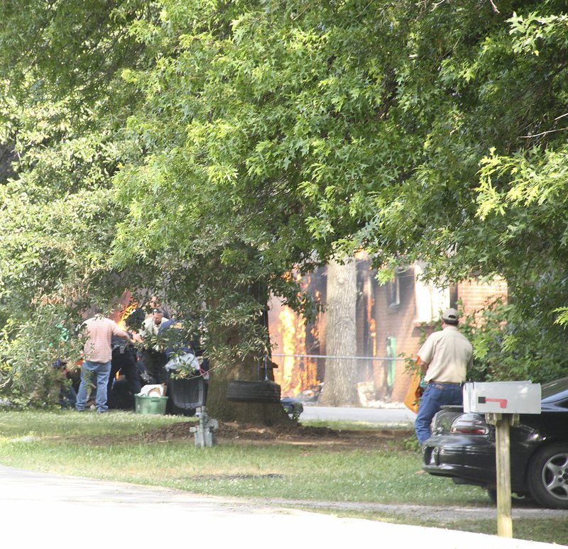 LYNN KUTTER ENTERPRISE-LEADER Law enforcement officers tend to a shooting incident as a house at 133 Neal St., in Farmington is engulfed in flames in the background. Randy Blecher, 50, of Farmington, died following a stand-off and officer-involved shooting Friday night.