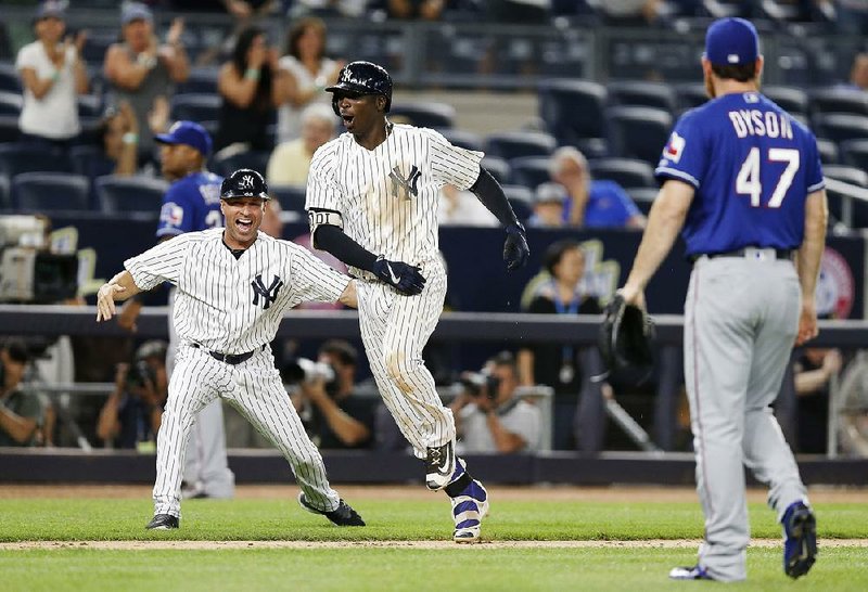 Didi Gregorius (center) celebrates with New York Yankees third-base coach Joe Espada (left) after hitting a game-winning, two-run home run against the Texas Rangers at Yankee Stadium in New York on Wednesday night. The Yankees scored six runs in the bottom of the ninth inning to earn the victory.