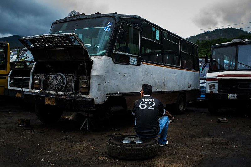 A driver works on the brakes of his bus in a parking lot on the outskirts of Caracas, Venezuela, on June 22. 