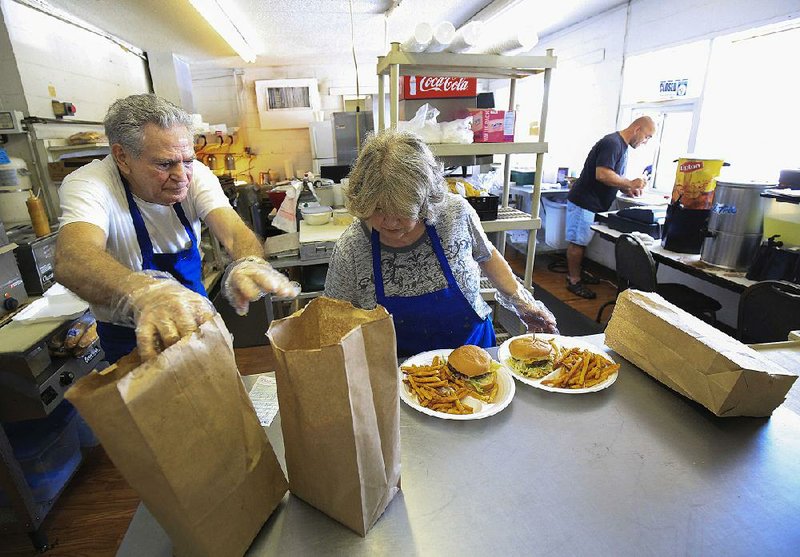 Bill and Billie Jean Huey work together in a well-practiced routine filling lunchtime orders Wednesday at the Fourche Dam Dairy Bar as Donny Kennedy (right) takes more orders at the window.