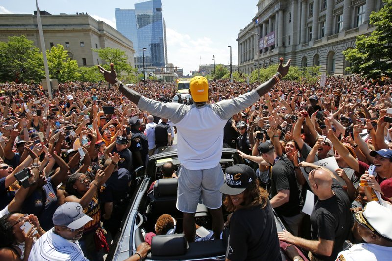 In this June 22, 2016, file photo, Cleveland Cavaliers' LeBron James, center, stands in the back of a Rolls Royce as it makes its way through the crowd lining the parade route in downtown Cleveland, celebrating the basketball team's NBA championship.