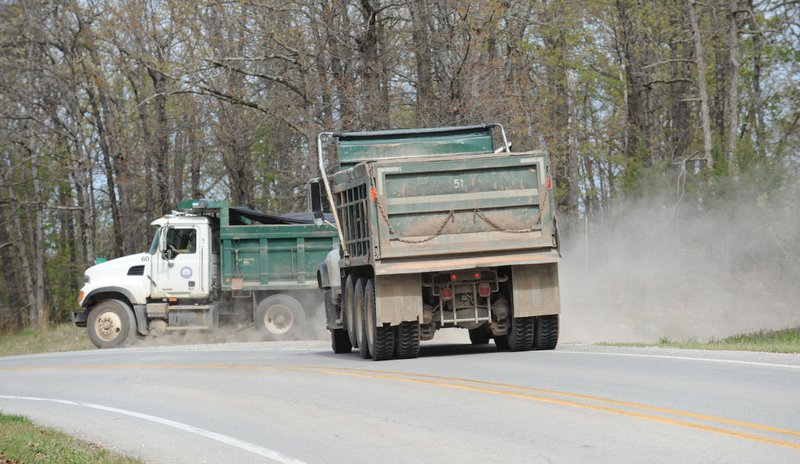 Dump trucks with the Washington County Road Department exit a gravel road onto Arkansas 16 Thursday, April 7, 2016, after leaving the Lindsey Pit, a red dirt pit just west of the Fayetteville city limits.