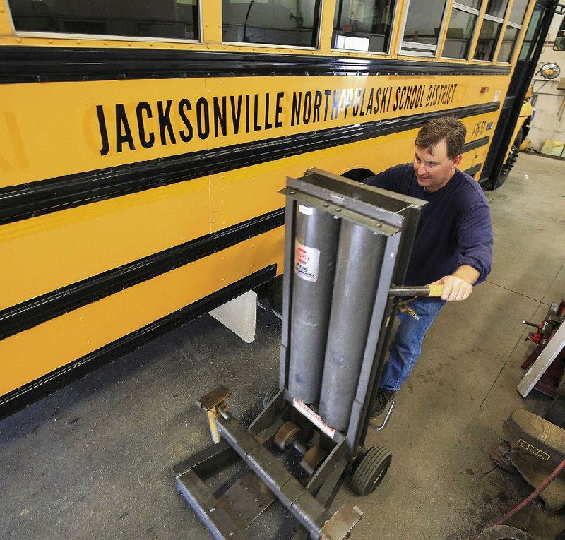 FILE PHOTO: Diesel mechanic Jesse Nix positions a lift Thursday, June 30, 2016 while working on a newly marked bus for the Jacksonville/North Pulaski School District. The bus is one of 78 moved from the Pulaski County district.