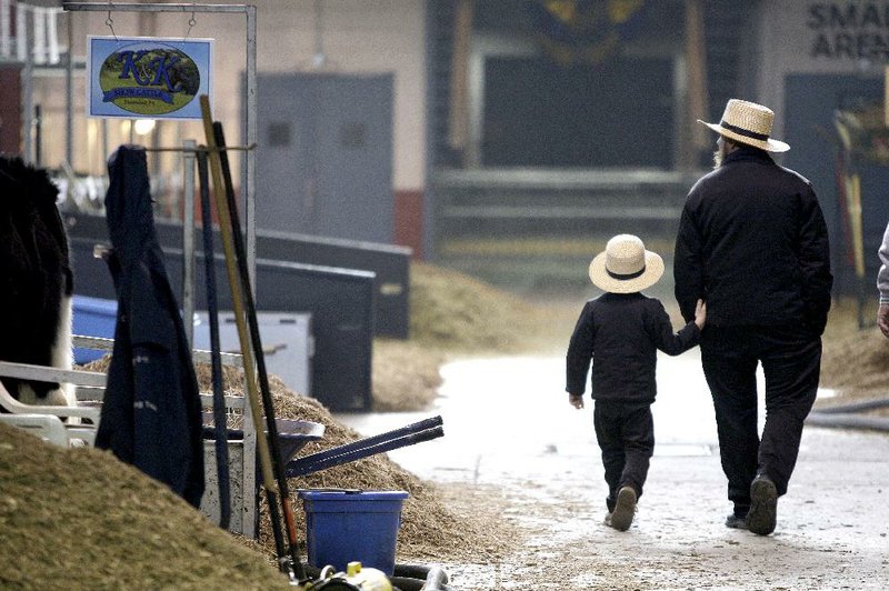 An Amish father and son walk together at a farm show in Pennsylvania. The number of Amish is on the rise, with new settlements being established in South America and Canada. 