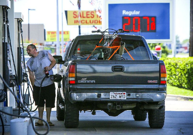 Richie Trott of Little Rock pumps gas for $2.07 a gallon Thursday at an Exxon station on University Avenue in Little Rock. A slump in the global oil market has produced some of the cheapest gasoline prices in a decade.