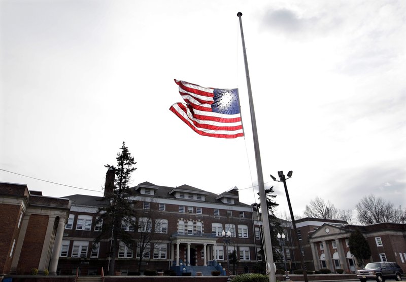 In this Feb. 12, 2012 file photo, an American flag flies at half-staff in front of the Whitney E. Houston Academy of Creative and Performing Arts in East Orange, N.J., to honor the performing artist Whitney Houston, who died the previous day. The honor once reserved for slain police officers, politicians and war heroes is more commonly extended to sports heroes and entertainers.