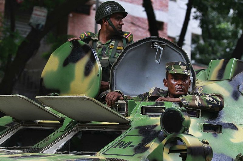 Soldiers who arrived in armored vehicles keep watch Saturday in Dhaka, Bangladesh.