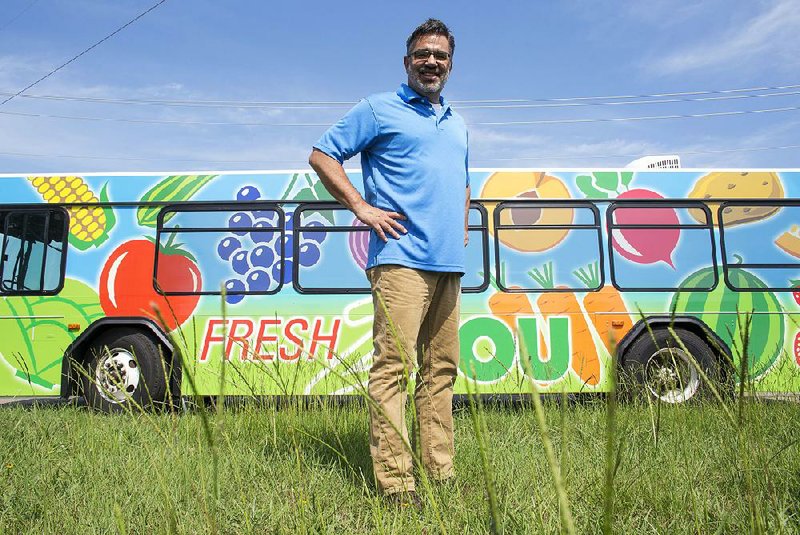 Pastor Mark DeYmaz of the Mosaic Church of Central Arkansas stands in front of a repurposed bus that will soon hold produce for a mobile farmers market. The bus will roll into low-income neighborhoods to sell fresh produce.
