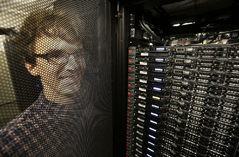 Massachusetts Institute of Technology researcher Carl Vondrick looks through a protective door while standing next to a computer server cluster (right) at MIT in Cambridge, Mass. MIT says binge-watching TV could help computers learn artificial intelligence.