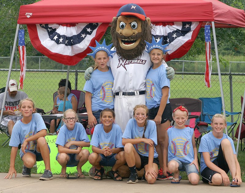 Photo by Randy Moll Strike, mascot for the Northwest Arkansas Naturals, posed for a photo with team members of the Gentry 11U softball team at the Freedom Festival held on Monday, July 4th, in Gentry. The girls were selling tickets to a Naturals&#8217; game as part of a fundraiser for their trip to play in the softball world series.