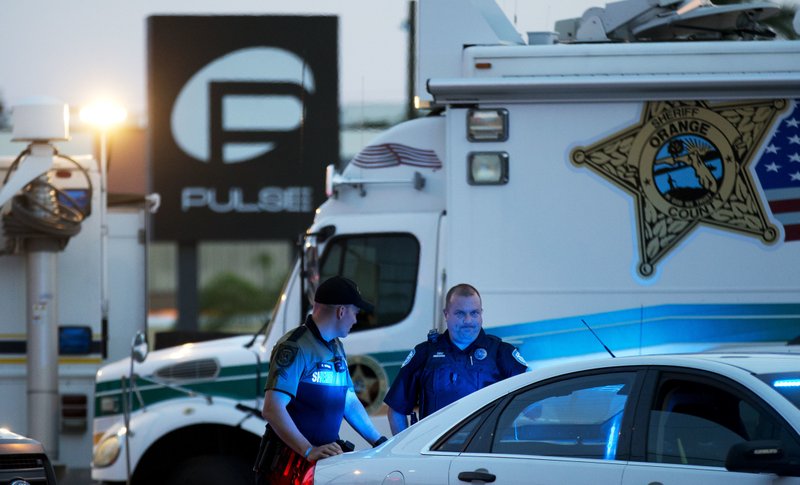 FILE - In this June 17, 2016 file photo, law enforcement officials stand outside the Pulse nightclub following Sunday's mass shooting, in Orlando, Fla. More police departments are exploring technology that would allow 911 emergency dispatchers to receive text messages from people who need help. When gunshots rang out at the Pulse nightclub in Orlando last month, patrons hid from the gunman and frantically texted relatives to call 911 because Orlando doesn't have 911 texting. (AP Photo/David Goldman, File)