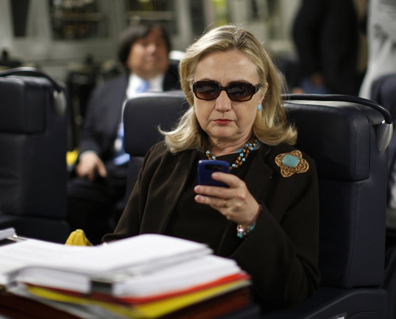 FILE - In this Oct. 18, 2011, file photo, then-Secretary of State Hillary Rodham Clinton checks her Blackberry from a desk inside a C-17 military plane upon her departure from Malta, in the Mediterranean Sea, bound for Tripoli, Libya. The State Department is under fire in courtrooms over its delays turning over government files related to Hillary Clinton&#x2019;s tenure as secretary of state. In one case, the department warned it needed a 27-month delay, until October 2018, to turn over emails from Clinton&#x2019;s former aides. (AP Photo/Kevin Lamarque, Pool, File)