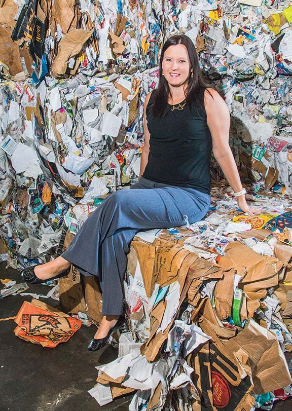 Alicia Neppl, the new recycling coordinator for the city of Conway, sits on a pile of bundled cardboard that has been sorted and made ready to ship out, along with the other stacks of cans, paper and plastics that the center collects at the Conway Sanitation Department.
