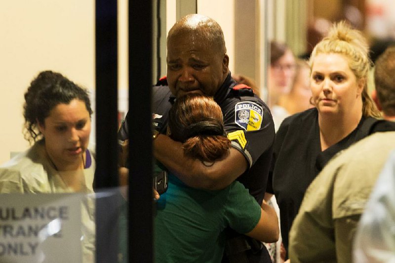 A Dallas transit agency police officer is comforted Thursday at Baylor University Hospital’s emergency room after several of the agency’s officers were shot.