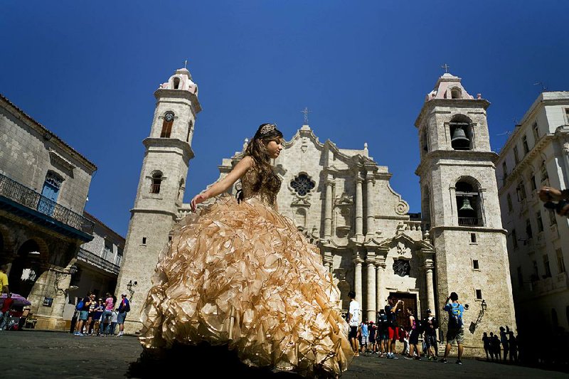 A “quinceanera” poses during her photo session in March in front of Havana’s Cathedral of the Virgin Mary of the Immaculate Conception as tourists line up to enter the building. Scheduled commercial airline service to Havana from 10 U.S. cities won tentative government approval Thursday.