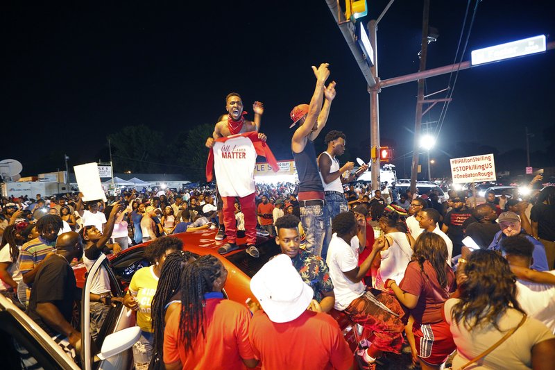 Protesters stand on cars as they congregate at N. Foster Dr. and Fairfields Ave., the location of the Triple S convenience store in Baton Rouge, La., Wednesday, July 6, 2016. Alton Sterling, 37, was shot and killed outside the store by Baton Rouge police, where he was selling CDs. 