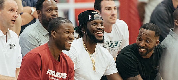 Arkansas assistant basketball coach T.J. Cleveland sits next to his cousin and current NBA player DeMarre Carroll while watching Carroll's AAU Team Friday at the Adidas Gauntlet Finale in Spartanburg, S.C.